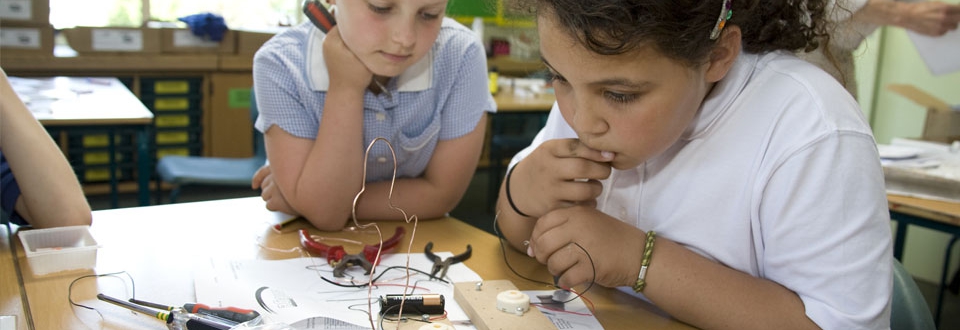 Two young girls working on an electrical game in a classroom