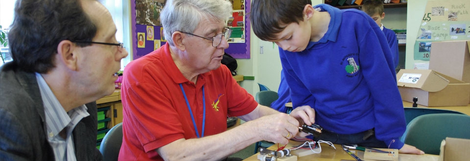Teacher showing a young boy how to wire up an electrical device