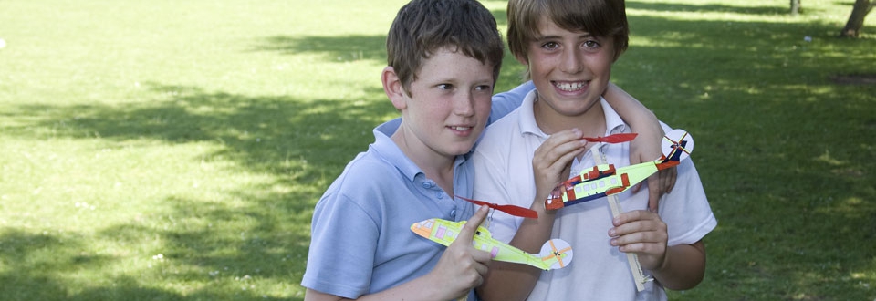 Two young boys holding rubber band powered model helicopters