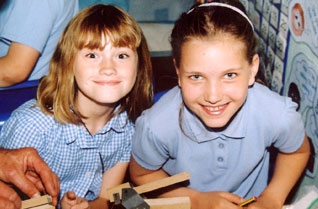 Two young girls smiling in a classroom