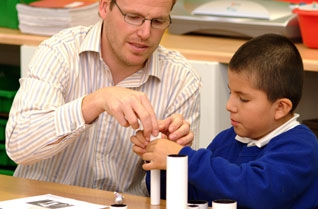 Teacher showing a young boy how to make a telescope