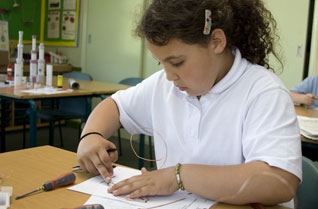 Young girl using pliers to bend electrical wire