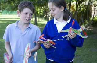 Young girl and boy holding rubber band powered model helicopters