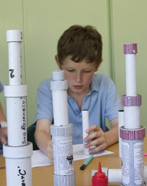 Young boy making a cardboard tube telescope in a classroom