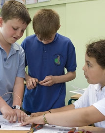 Three children bending wire with pliers to make a steady hand game