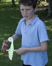 Young boy winding the propeller on a model helicopter outside