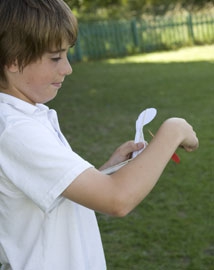 Young boy winding the propeller on a model helicopter outside
