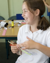 Young girl winding the propeller on a model helicopter in a classroom
