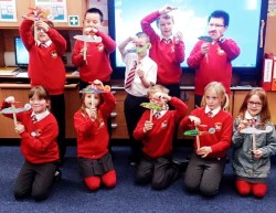 Group of little children in red jumpers with card aeroplanes
