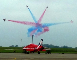 Four aircraft in special display with red and blue trails, red aircraft on ground