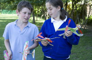 Young girl and boy holding rubber band powered model helicopters